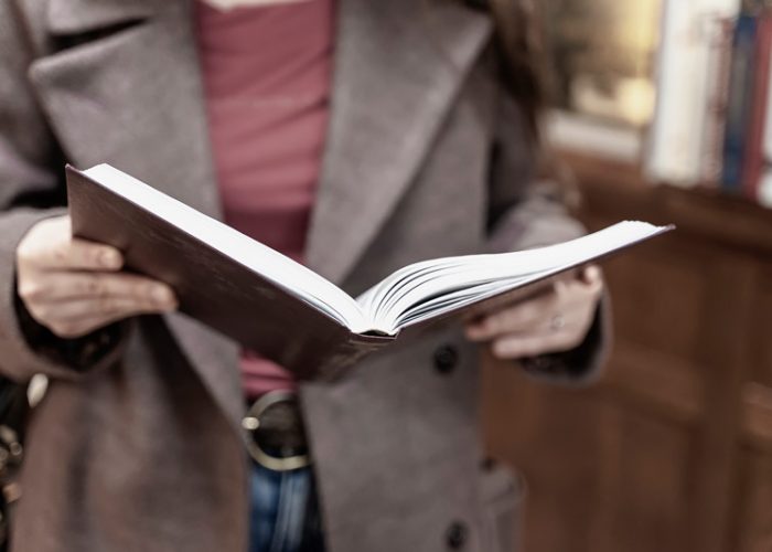 Woman with book open in her hands, in a bookstore